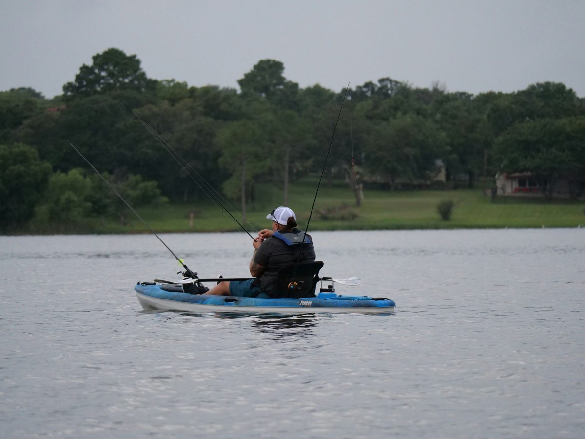 Angler fishing from a kayak while properly wearing a PFD life jacket