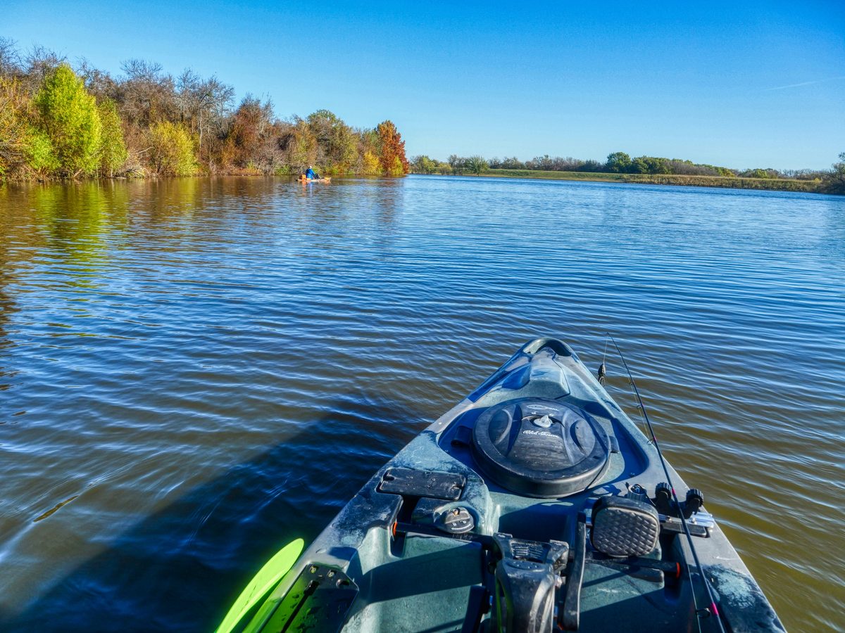 View from the bow of a fishing kayak on calm water on a fall day