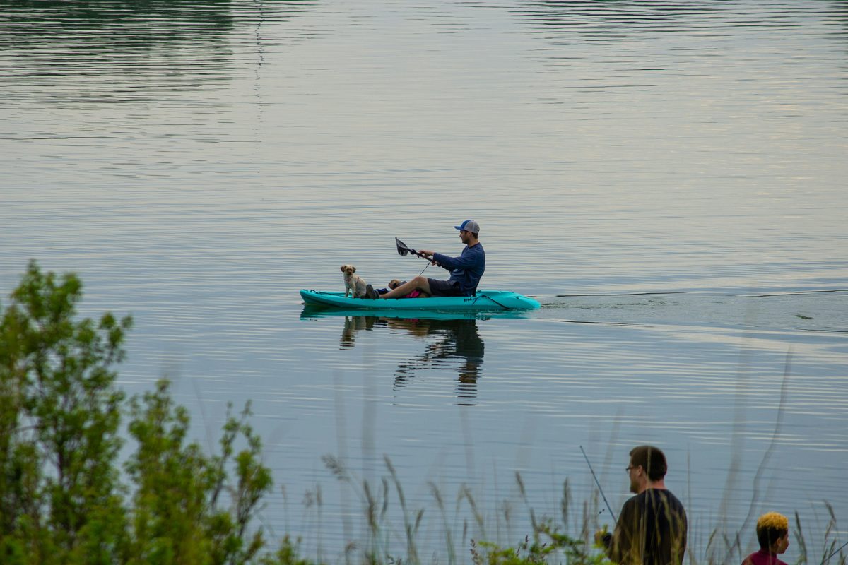 Man and his dog enjoying a calm evening kayak fishing trip on the lake